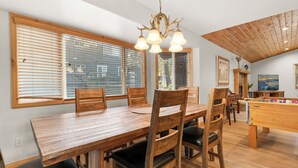 Un espace repas avec une table et des chaises en bois, un lustre et une table de baby-foot.