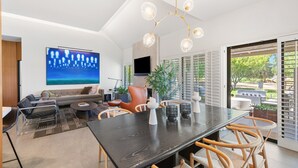 Una sala de estar moderna con un televisor de pantalla plana grande, un comedor de madera oscura y un espacio de descanso cómodo.