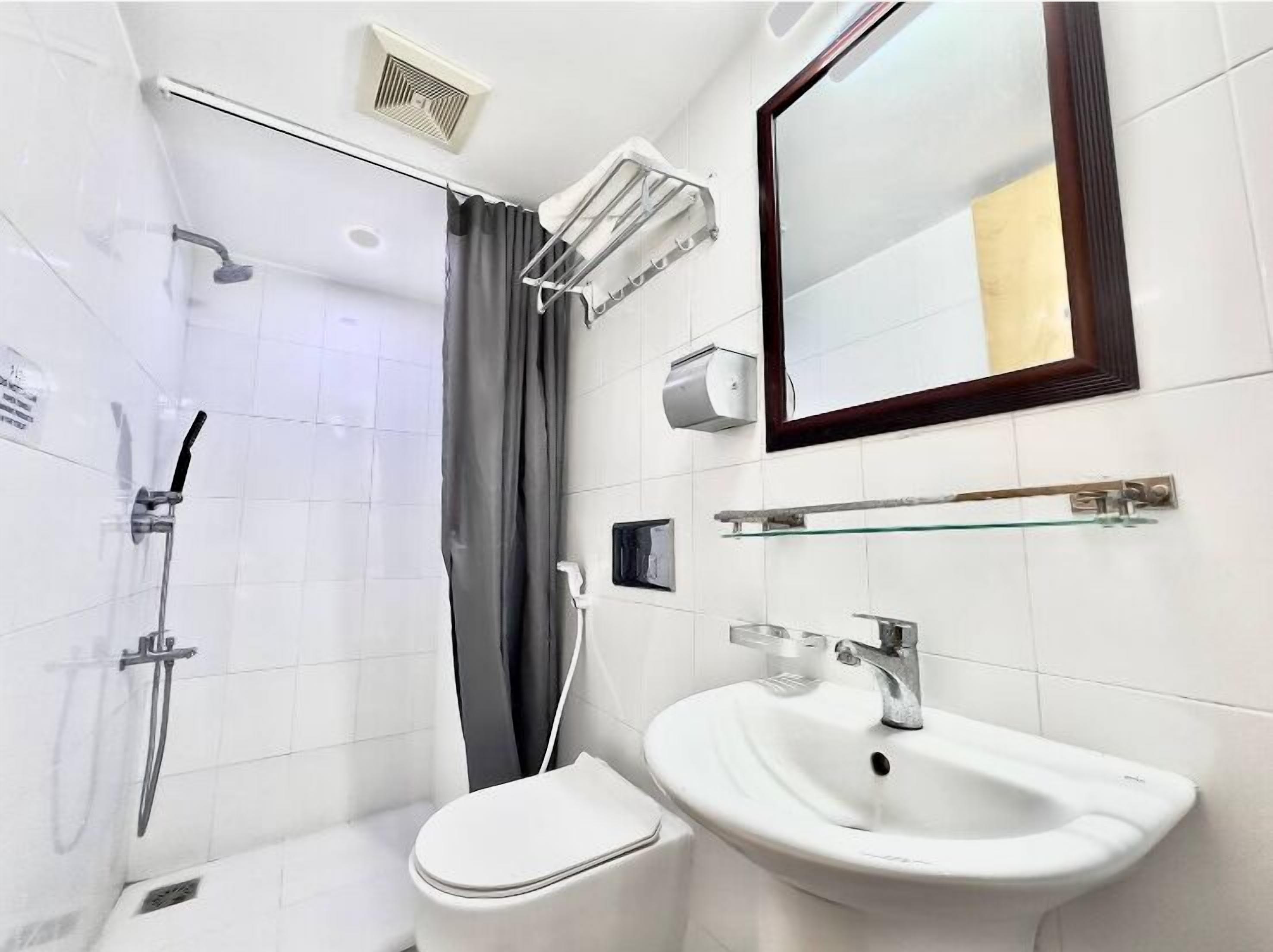 Uma casa de banho moderna com chuveiro, sanita e lavatório.
