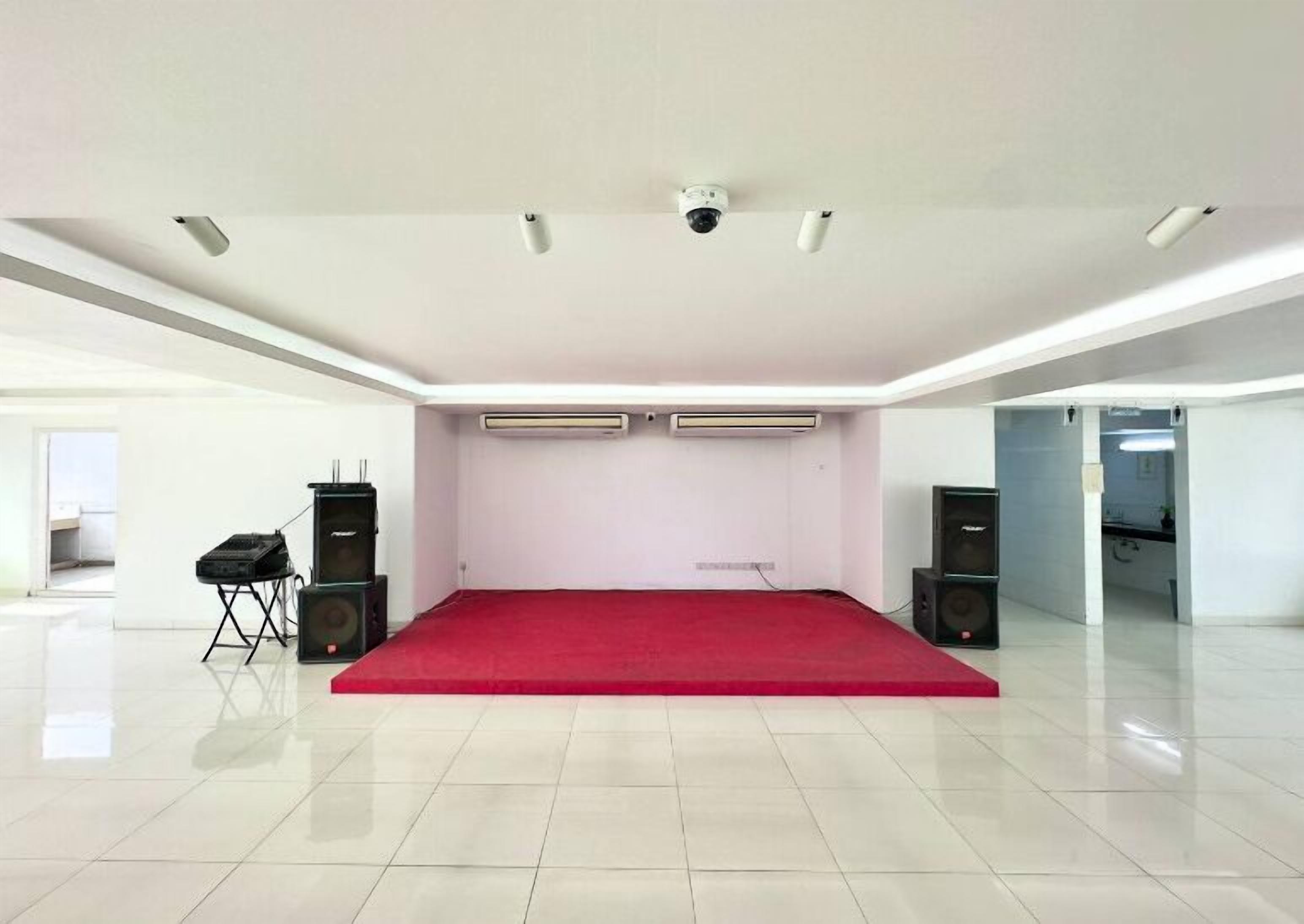 A spacious room with a red carpet, white walls, and ceiling-mounted air conditioning units.
