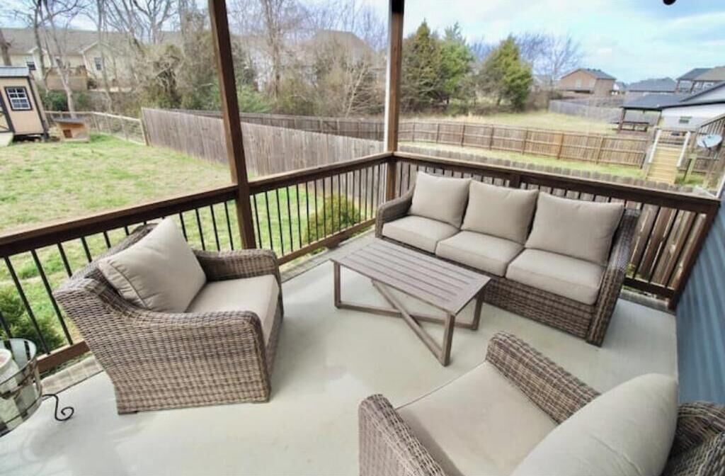 A covered patio with wicker furniture, including a sofa and chairs, and a small table.