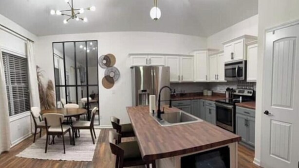 A modern kitchen with white cabinets, a wooden island, and a dining area with chairs and a table. - Beautiful, Cozy  and Airy Retreat with Lots of Character - NO CLEANING FEE (Clarksville)
