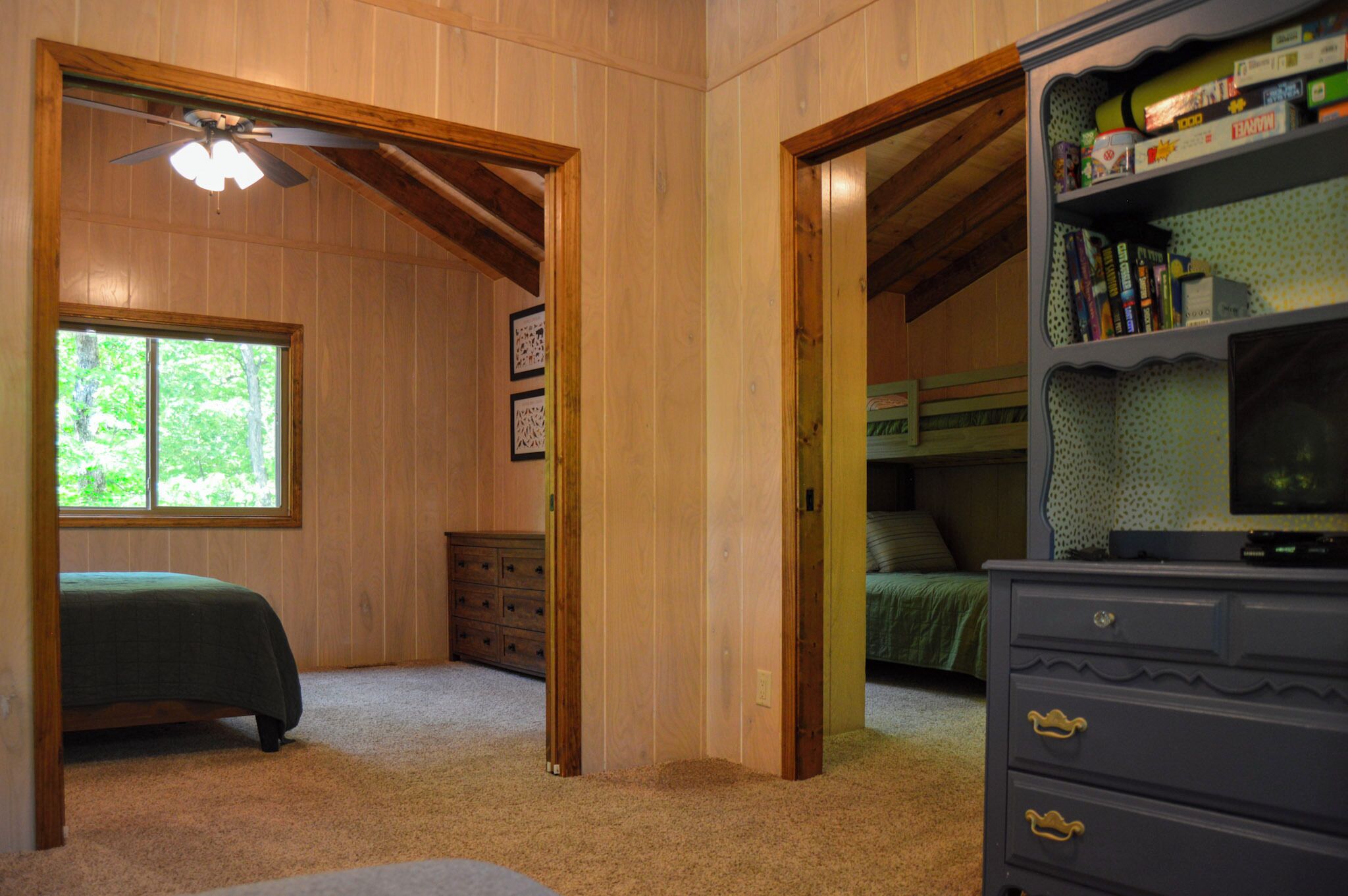 A bedroom with a bed, a dresser, a bookshelf, and a window.