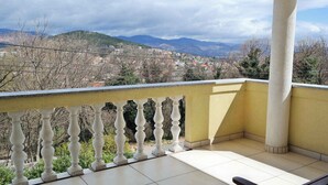 A balcony with a view of a town and mountains.