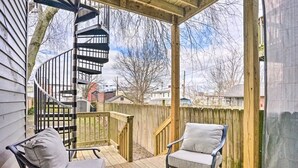 A covered outdoor deck with a spiral staircase, two chairs, and a view of the neighborhood. - Charming Historic 1-bedroom apartment with WiFi, AC in pleasant Richmond (Richmond)