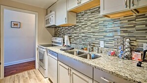 A modern kitchen with white cabinets, a granite countertop, and a backsplash with multicolored tiles. - Charming Historic 1-bedroom apartment with WiFi, AC in pleasant Richmond (Richmond)