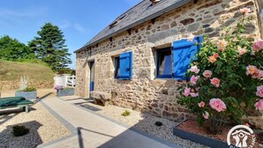 A stone building with blue shutters, a paved pathway, and a garden with pink flowers. - Ty Luz - CAMLEZ - Gîte (CAMLEZ)