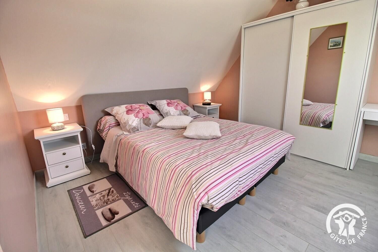 Une chambre à coucher comprenant un lit, des tables de chevet, une commode, un miroir et une armoire.
