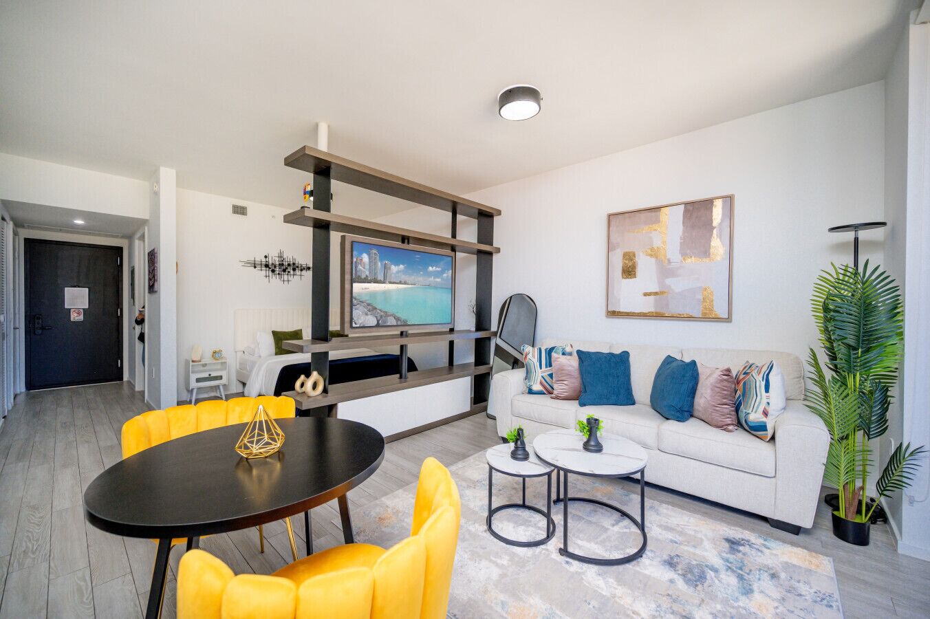 A modern living room with a sofa, yellow chairs, a coffee table, and a TV mounted on a wall.