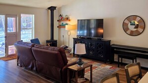 Un salon avec un canapé en cuir marron, un téléviseur, une cheminée et un coin repas comprenant des chaises et une table.