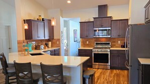 Une cuisine moderne dotée d’un îlot central, de meubles en bois foncé, d’appareils électroménagers en acier inoxydable et d’un plancher en bois.