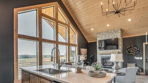 A modern kitchen with a large island, a stone fireplace, and a view of the outdoors.