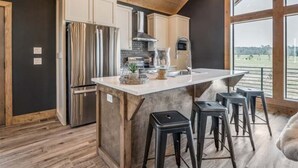 Une cuisine moderne dotée d’un îlot central, de tabourets de bar et offrant une vue sur l’extérieur.