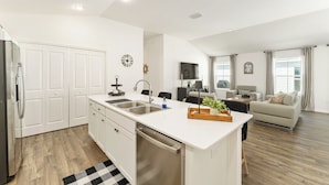 A modern kitchen with white cabinetry, a built-in dishwasher, and a central island with a sink. - DISCOUNTED 2-bed Patio Villa in Waters Edge, near Eastport. Avail. Nov, Dec, Jan (The villages)