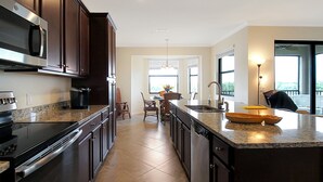 Une cuisine moderne avec des meubles en bois foncé, des appareils en acier inoxydable, un plan de travail en granit et un grand îlot central doté d’un évier.