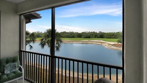 Un balcon avec vue sur un lac, un terrain de golf et des palmiers.