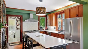 A modern kitchen with a large island, stainless steel appliances, and wooden cabinets.