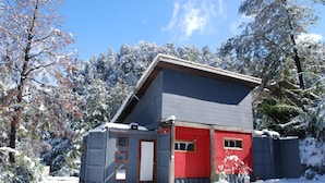 A cabin with a sloped roof, a red door, and a grey exterior. - Fehu Container Lofts (Villa La Angostura)