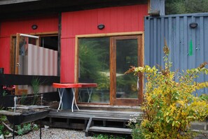 Stylish home with a deck and garden, featuring a bathtub and a shipping container addition.