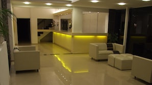 A modern living room with a sofa, a coffee table, and a kitchen area with a yellow-lit counter. - Hotel Santander (Villa Carlos Paz)