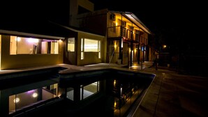 A nighttime view of a hotel with a swimming pool, outdoor lighting, and a staircase leading to the entrance. - Hotel Santander (Villa Carlos Paz)