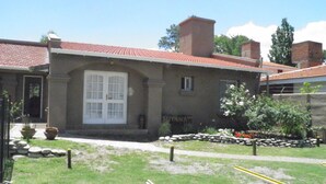 A building with a red-tiled roof, a white-framed window, and a stone wall. - Hosteria Suyana (San Salvador de Jujuy)