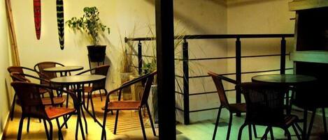 A patio area with a round table and chairs, a potted plant, and a wall-mounted decorative item.