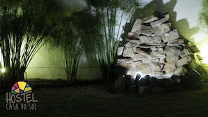 A rock formation with a water feature, surrounded by tall grasses and a wall.