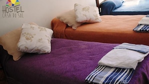 A hostel room with two beds, each with a different colored bedspread and pillows.