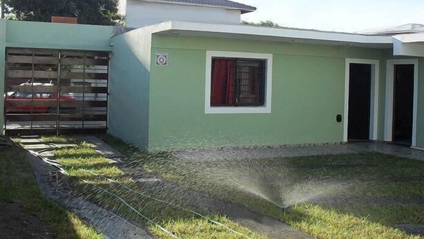 Una casa de un piso con garaje, un pequeño jardín delantero y una ventana con cortinas rojas.