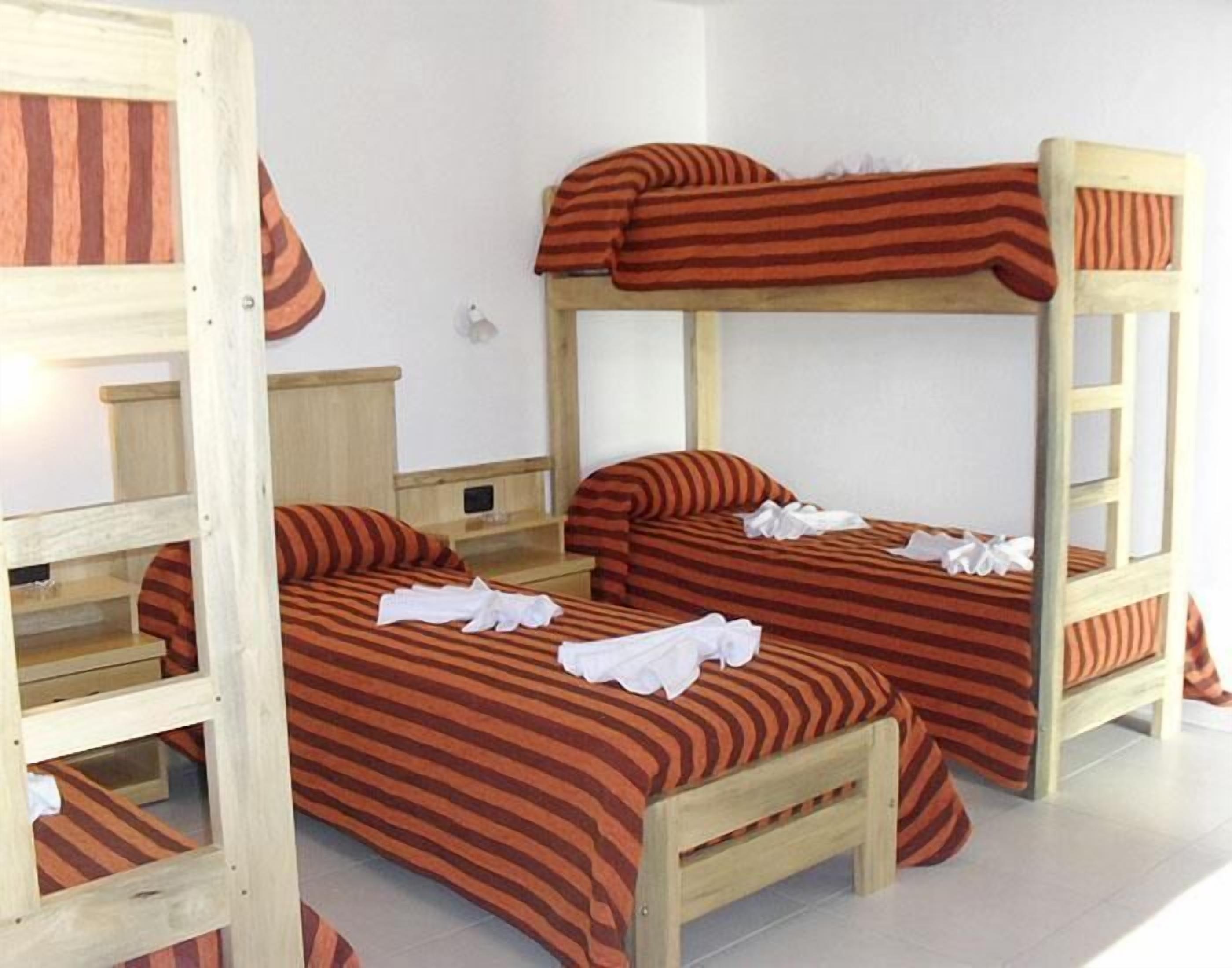 A bunk bed room with striped bedding and a wooden ladder.