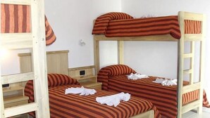 Habitación con literas, ropa de cama a rayas y cabecero de madera.