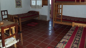 Une chambre de dortoir avec deux lits simples, une table en bois et une chaise.