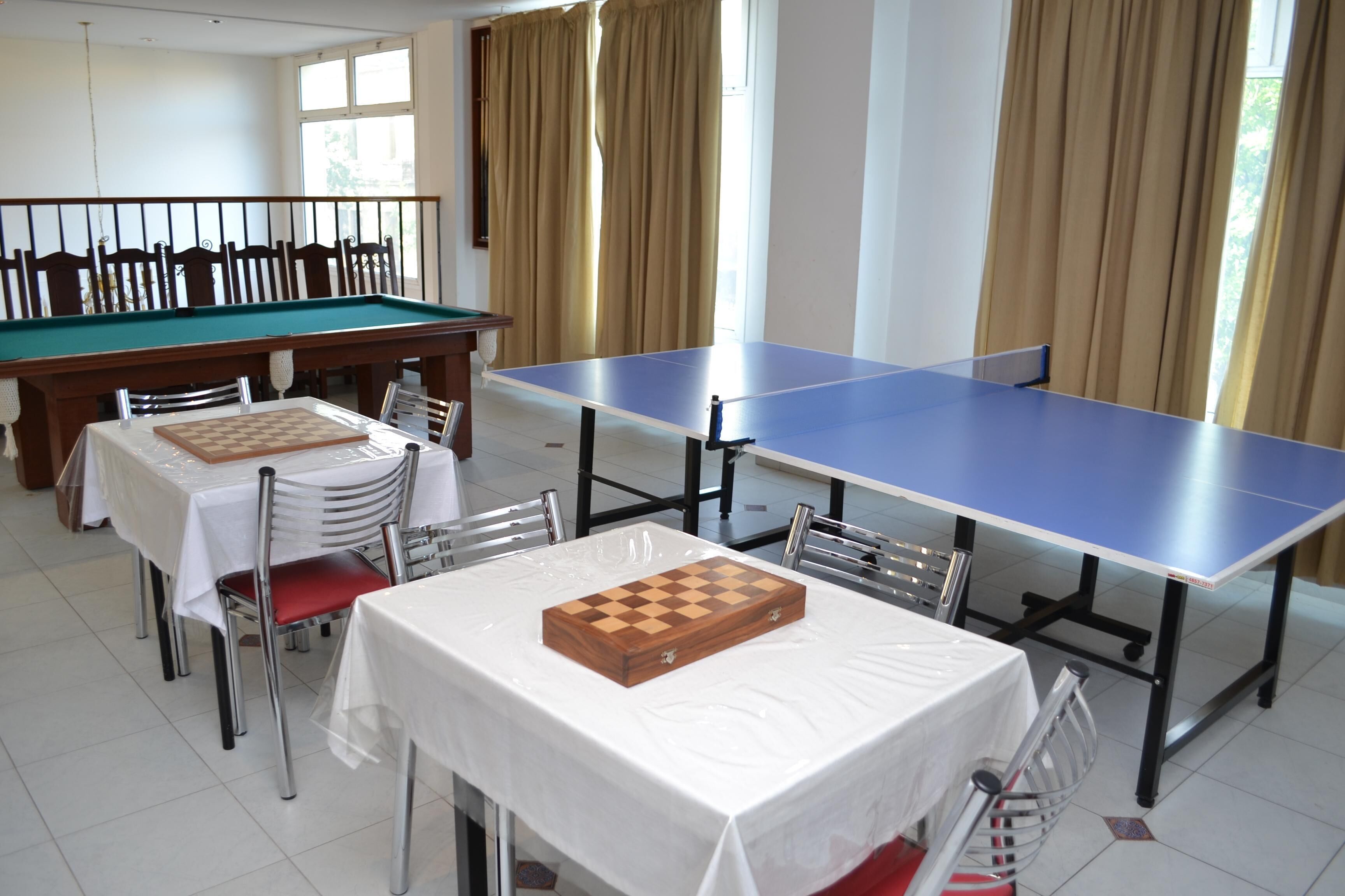 A room with a pool table, a ping pong table, and a chess table.