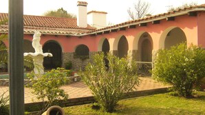 Un cortile con una statua, finestre ad arco e un tetto in tegole.