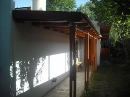 Un edificio moderno con un espacio exterior cubierto, ventanas amplias y suelo de piedra.