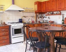 Una cocina con armarios de madera, una estufa y una mesa de comedor con sillas.