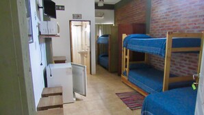 A dormitory room with bunk beds, a small refrigerator, a sink, and a window with a view of a brick wall. - La Casona (Gualeguaychú)