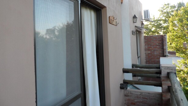 A building with a large window, a wooden staircase, and a brick wall. - La Casona (Gualeguaychú)