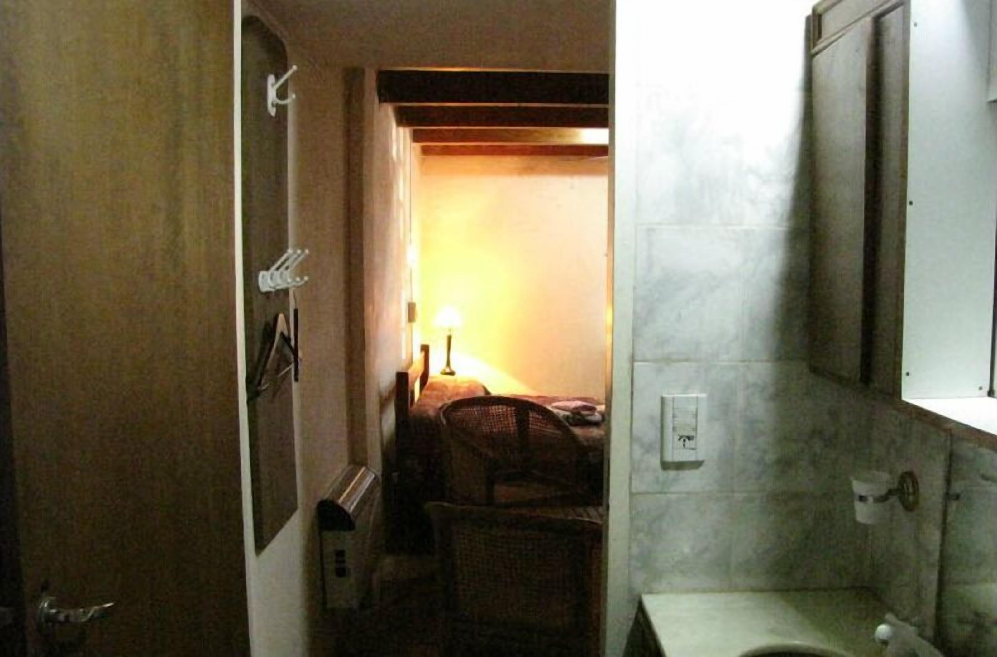 A narrow hallway leading to a bathroom with a toilet, a sink, and a mirror.