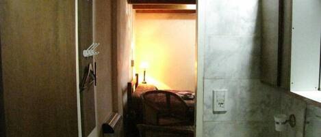 A narrow hallway leading to a bathroom with a toilet, a sink, and a mirror.