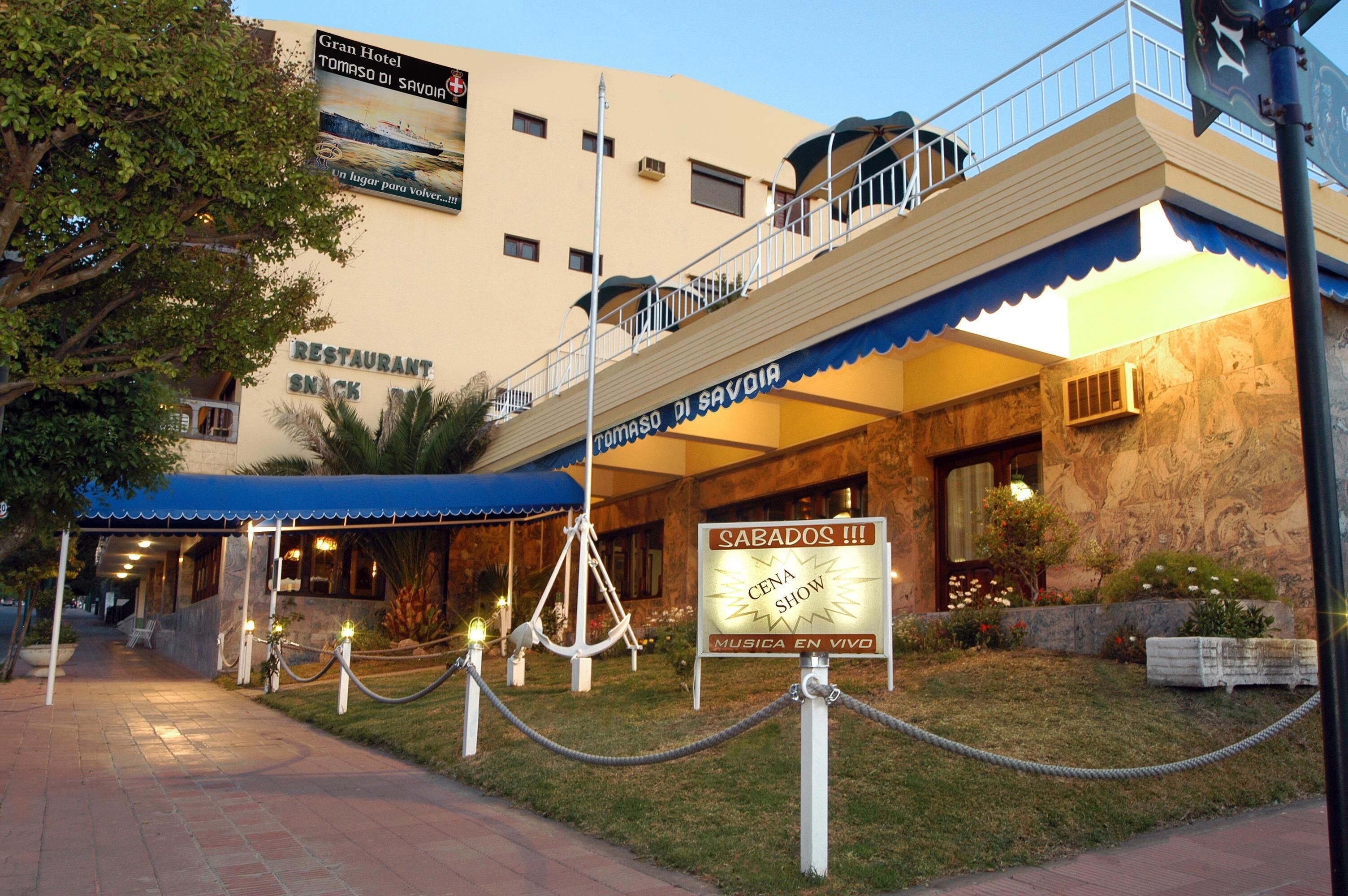 Un hotel con un restaurante llamado 'RESTAURANT SNACK' y un cartel que anuncia 'SABADOS!!! CENA SHOW MÚSICA EN VIVO'.