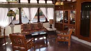 A cozy interior with a wooden sofa, two chairs, a small table, and a window with curtains. - Gran Hotel Tomaso Di Savoia (La Falda)