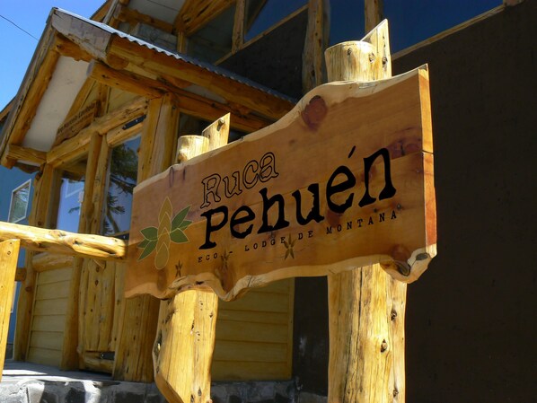 A wooden sign with the text "Ruca Pehuén" and "Eco-Lodge de Montaña" indicating a lodge's name and type.