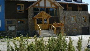 A lodge with a stone facade, wooden entrance, and a sign indicating it is a 'Pehuén' lodge. - Ruca Pehuen Eco Lodge de Montaña (Caviahue)