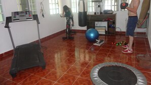 A gym with exercise equipment, a punching bag, and a trampoline. - Paakal's Hostel (Chetumal)
