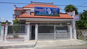 A two-story building with a red-tiled roof and a sign advertising 'PAAKAL'S GROUP' as a travel agency, tourist transportation, and hostel. - Paakal's Hostel (Chetumal)