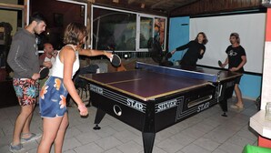 Un tavolo da ping pong in una stanza con travi in legno a soffitto e una lavagna a parete.