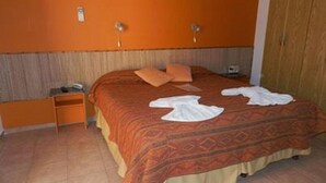 Une chambre d’hôtel avec un lit, une table de chevet et une armoire.