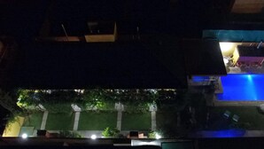 Vue nocturne d’un espace piscine avec un patio et des sièges d’extérieur.